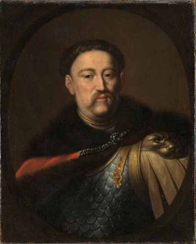 Obraz olejny. Przedstawia realistyczny portret Jana III Sobieskiego. Król ubrany w zbroję, z płaszczem na ramionach. Wizerunek namalowany jest realistycznie z dbałością o każdy szczegół.