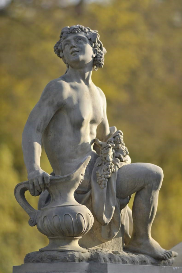 Rzeźba ogrodowa młodego chłopca z dzbanem i winoroślą w ręku i na głowie.