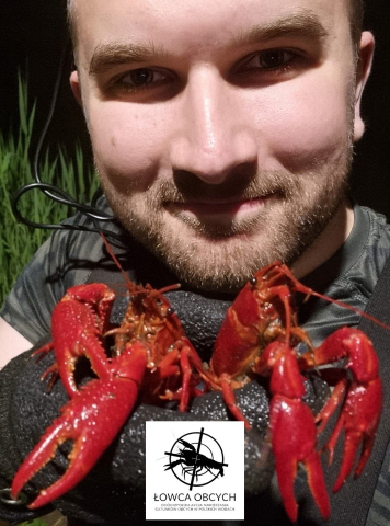 Zdjęcie portretowe mężczyzny z zarostem, który trzyma dwa czerwone raki.